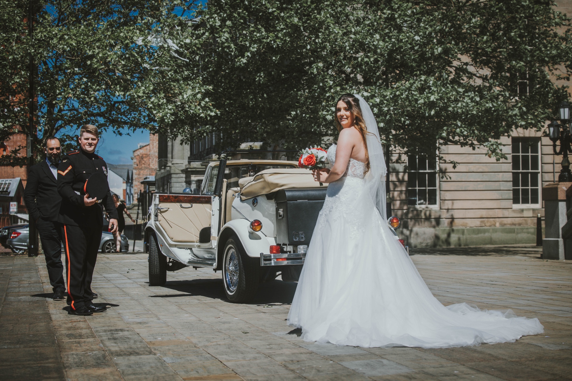 Bride arriving at the ceremony beside a vintage wedding car
