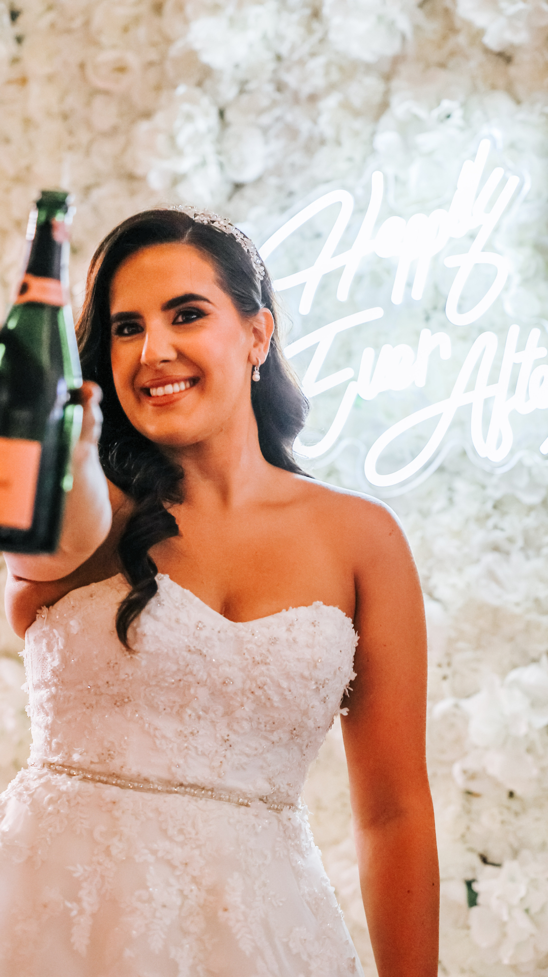 Bride with champagne by the flower wall