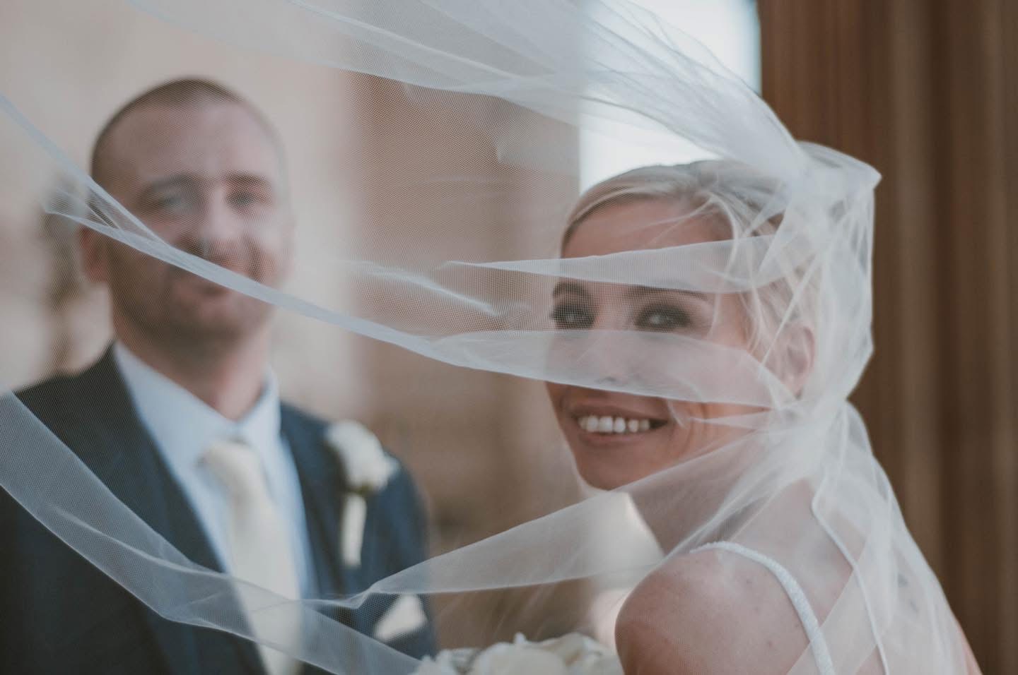 Bride laughing behind a veil in the wind